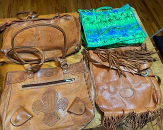 Bottom Left to Right: Berne Fleur-de-Lis Leather Tote Bag. $45. Berne Hand-Tooled Fringe Bag. $40. Top Left to Right:  Hand-Tooled Floral Satchel $25. St. Lucia Caribbean Souvenir Tote. $5