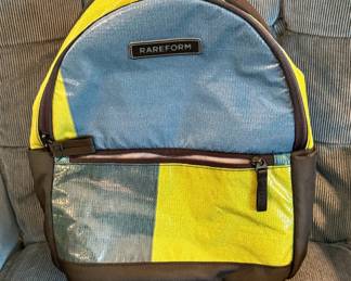 A Rareform Mini Everyday Backpack featuring a unique blue and yellow recycled billboard patchwork design.