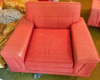 We have two coral-pink textured mid-century modern armchairs that feature classic button tufting and wide, structured arms.