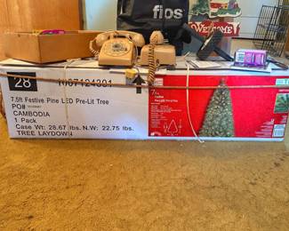 A Home Accents Holiday 7.5 ft. Festive Pine LED Pre-Lit Artificial Christmas Tree packaged in its shipping box.