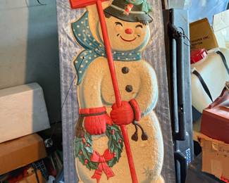 This vintage holiday decoration features a festive snowman holding a "Merry Christmas" sign and a wreath.