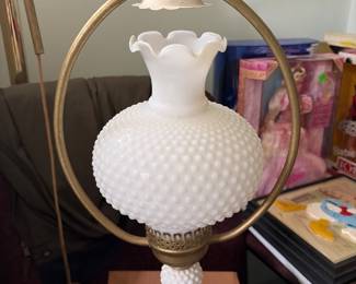 Vintage hanging swivel hurricane lamp features a white milk glass hobnail globe with a ruffled chimney shade suspended in a brass-finish 