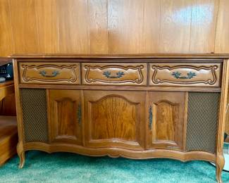A mid-century Magnavox Astro-Sonic solid-state stereo console featuring a French Provincial style wood cabinet with decorative hardware, side speaker grilles, and a top-loading audio system including a turntable and AM/FM radio