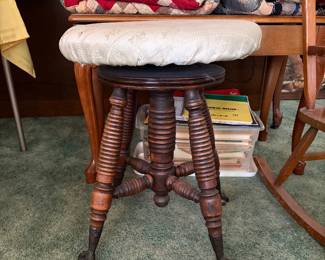 This vintage Victorian adjustable piano stool features intricately turned wooden spindle legs with classic cast iron and glass claw-and-ball feet.