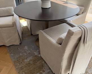 set of four RH Low Belgian Slipcovered Track Arm Dining Chairs with matching lumbar pillows, and the RH Aero Round Dining Table with dark walnut top and antiqued brass pedestal base,