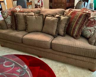 The Earth tone, traditional, three cedar Sofa features, rolling arms, exposed wooden bun, feet and arrangement of matching pattern throw pillows