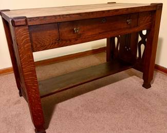 Antique Arts & Crafts / Mission-style tiger oak library table with single drawer, lower shelf, substantial legs, and decorative pierced side panels. Beautiful quarter-sawn/tiger oak grain and strong period styling. Researched prior to sale.