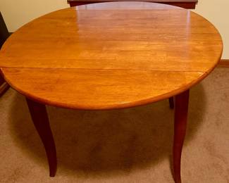 Vintage wood drop-leaf dining table with hinged sides that fold down for a smaller footprint and lift up for additional table space. Warm wood finish, graceful tapered legs, and a practical space-saving design. Researched prior to sale.