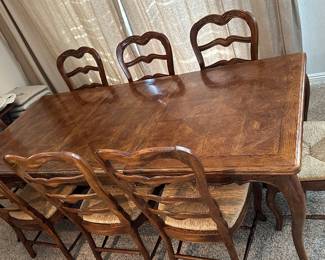 vintage French Country / Provincial style extension dining table paired with classic rush-seat ladderback chairs.