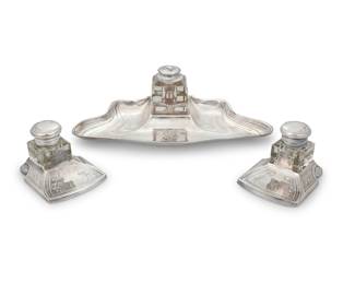 1182 An Argenta silver plated ink stand Early 20th century Marked: ARGENTA XO; two associated inkwells marked: MADE IN PORTUGAL The Art Nouveau stand with glass bottle, together with two silver-plated metal and glass inkwells 3 pieces Inkstand and well overall height 3 3/8 in., width 10 5/8 in., depth 5 1/2 in.; each associated height 2 5/8 in., width 3 1/8 in., depth 3 3/4 in. Estimate: $200 - $300