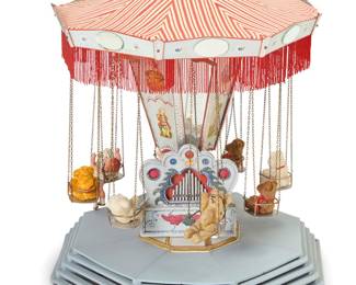 1089 A Folk art wood and tole tabletop carousel Early/mid-20th century, probably Joseph Miller Wiener Prater model Unmarked Painted metal mounted with printed paper figures, the rotating top fitted with metal chains and chairs with plush toys and dolls, on a tiered wood base, electrified Height 33 1/2 in., width 27 in., depth 27 in. Estimate: $150 - $250