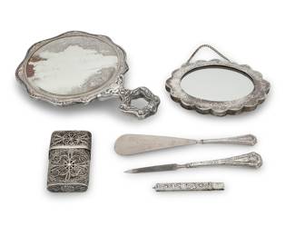 1127 A group of sterling silver and silver plated table items Late 19th/early 20th century Comprising sterling silver: a filigree business card holder, pencil case, shoehorn, and letter opener; silver-plated: two hand mirrors 6 pieces Largest mirror height 8 3/4 in., width 6 in., depth 1 1/4 in.; shoehorn length 7 in. Total weighable sterling 3.3 oz. troy approximately Estimate: $150 - $250