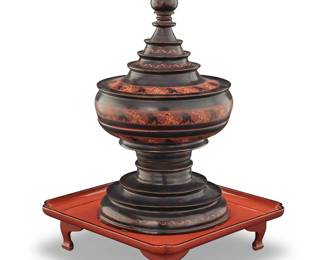 1078 A Southeast Asian lacquered wood offerings vessel 19th/20th century or later Depicting red on black elephants, comprising a turned lid, inner tray, and tiered base, raised on a possibly associated orange lacquered stand 2 pieces Vessel height 19 in., diameter 9 1/4 in.; stand height 3 3/8 in., width 12 3/4 in., depth 12 3/4 in. Estimate: $400 - $600