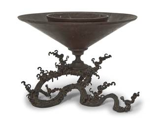 1199 A Japanese metal usubata ikebana vase 20th century The base in the form of roiling waves, issuing a cylindrical basin for floral display Height 7 1/4 in., width 12 1/2 in., depth 11 in. Estimate: $200 - $400