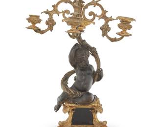 1297 A French parcel gilt bronze figural candelabrum Late 19th/early 20th century Each unmarked The putti-form standard issuing four lights, raised on an ornate scrolling foliate-form base Height 20 1/4 in., width 13 in., depth 8 3/4 in. Estimate: $150 - $250