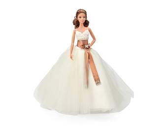 1201 Monique Lhuillier Limited Edition Gold Label Bride Barbie Doll Circa 2006, Designer Brides™ Series; model J0960 The Monique Lhuillier™ Bride Barbie® brunette doll with brown eyes wearing a bridal gown with a white lace bodice above a tulle full skirt with front pleats, sable brown satin sash with rhinestone floral brooch and embroidered faux pearl accents, accessorized with diamante stud earrings and ring, as well as lace undergarments, an off-white garter with blue ribbon detail, and removable shoes, with associated stand, and original display text plaque Height 12 in., width 4 in., depth 2 in. approximately; height with dress 16 in. Estimate: $40 - $60