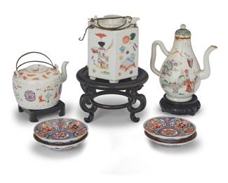 1019 A group of East Asian polychrome enameled porcelain tea wares 19th/20th century Some with various red underglaze marks; saucers with sticker: Made in Japan The assembled group comprising three Chinese teapots on wood stands, four Japanese saucers, and an associated footed cup painted with figural scenes (not pictured) 8 pieces Tallest teapot height 6 3/8 in., width 5 1/2 in., depth 3 3/8 in.; diameter of saucers 3 7/8 in. Estimate: $400 - $600