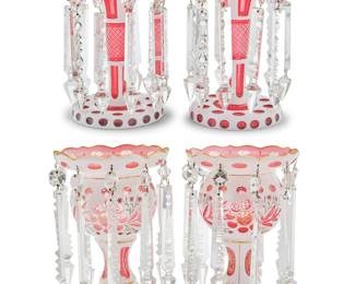 1167 Two pairs of Bohemian overlaid cranberry glass lusters Late 19th/early 20th century Each unmarked Mounted with cut glass drop elements, one pair painted with floral decoration and gilt accents 2 pieces Height of painted 11 1/8 in., diameter 7 1/4 in.; height of shorter 10 1/4 in., diameter 6 1/2 in. Estimate: $300 - $500