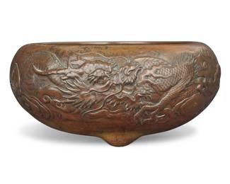 1048 A Chinese bronze jardinière Late Qing dynasty (1644-1912) Unmarked Depicting a dragon in low relief, raised on three protruding feet Height 6 in., diameter 14 in. Estimate: $400 - $600