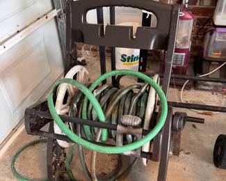 Freestanding plastic garden hose reel cart with hoses.
