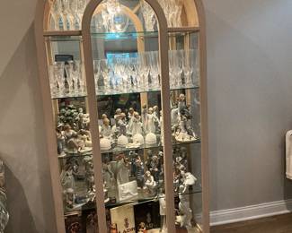 Arched curio cabinet with Fabergé stemware, Lladro, and Hummel collectibles