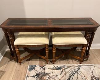 Vintage wooden console table with smoked glass inserts and two matching tucked under stools with light colored upholstered seats