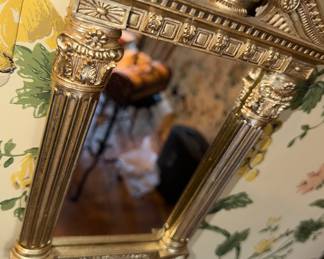 Ornate wall mirror features classical architectural columns