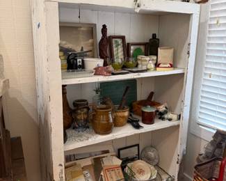 Chippy white primitive cupboard with antique bottles and stoneware