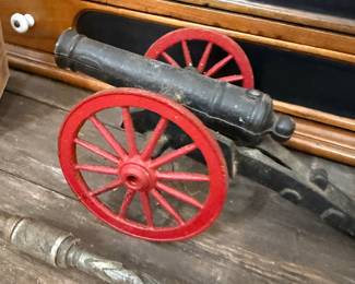 Cast iron toy cannon with red spoke wheels