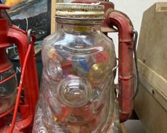 Jar of vintage marbles beside red barn lantern