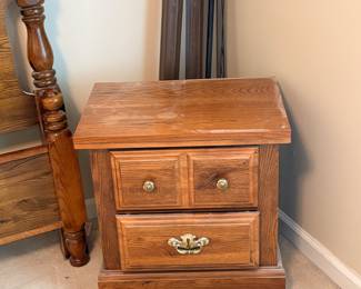 solid oak two-drawer nightstand with brass-toned hardware and a warm honey finish