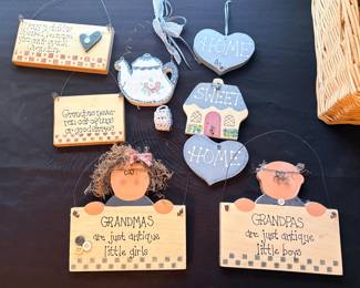 collection of handmade wooden and painted hanging signs and decorative plaques themed around grandparents and home, including character cutouts for "Grandmas" and "Grandpas."