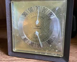 vintage mid-century modern Taylor Humidiguide desktop thermometer and hygrometer, featuring a square dark textured case, a round silver-toned dual-dial face, and dual indicators for measuring both ambient temperature and relative humidity.
