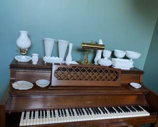 Everett "Dyna-Tension" upright console piano, constructed in a traditional wood cabinet finish. Photo also features a collection of white milk glass hobnail glasswares. Candy dishes. Vases. Lamp.
