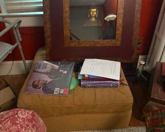 Large gold-framed wall mirror with decorative boxes, books, and collectibles below