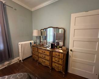 Vintage wood dresser with tri-fold vanity mirror in bedroom with hardwood floors