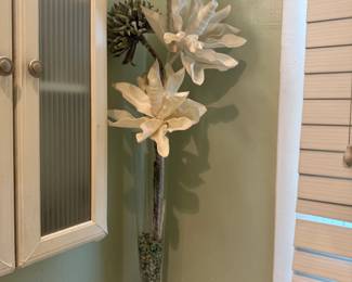Decorative silk flower arrangement in tall glass vase on bathroom vanity