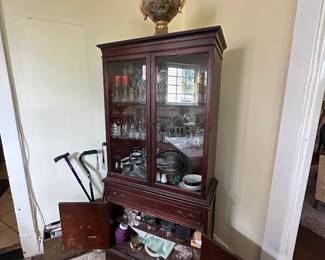 Antique glass-front display cabinet with decorative urn and collectibles