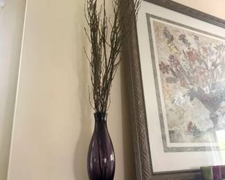 Decorative vase with dried branches on wood mantel shelf with framed artwork