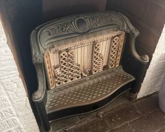 Antique cast iron fireplace insert with ornate decorative detailing