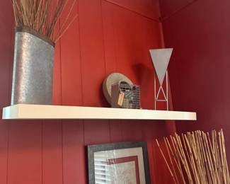 Decorative corner display with floating shelf, vases, dried branches, and framed artwork on red accent wall