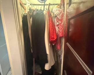 Closet full of vintage clothing, dresses, blouses, and accessories with hat