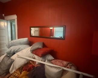 Bedroom with queen bed, white linens, red accent walls, and wall mirror