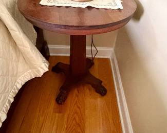 round wooden accent table featuring a carved pedestal base with distinctive paw feet