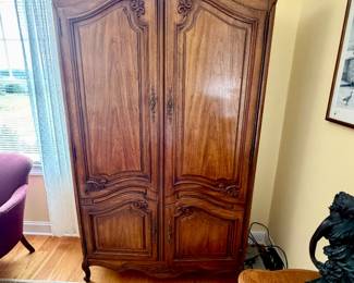 traditional French Provincial style wooden armoire featuring ornate hand-carved floral and scroll accents