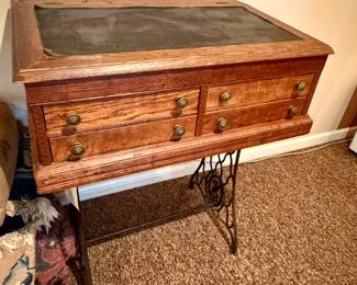 antique treadle sewing machine cabinet with a wooden multi-drawer top and a cast-iron base