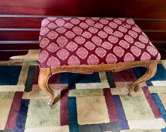 upholstered footstool featuring carved wooden cabriole legs