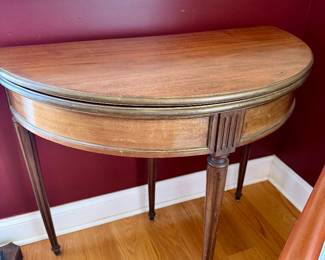 antique demilune flip-top card table featuring a vibrant green felt interior and elegant brass-banded wood trim