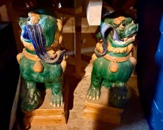 pair of Chinese sancai-glazed ceramic Foo Dogs (temple guardian lions) resting on ochre plinths
