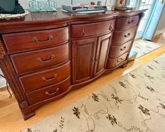 is an American Drew Cherry Grove door triple dresser, featuring a rich antique cherry finish and a graceful bowed front with ornate hardware